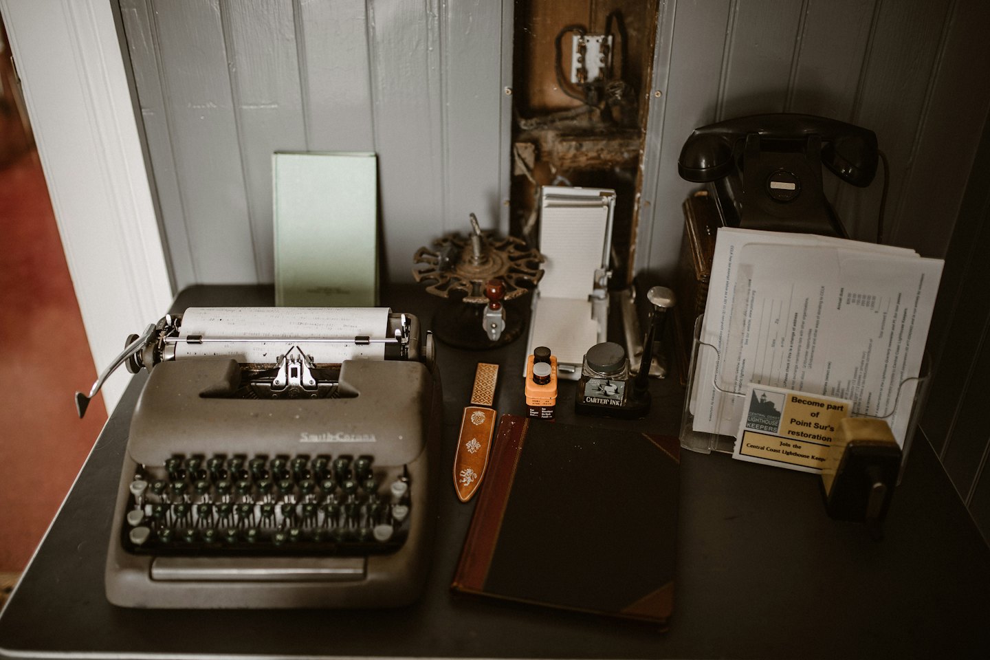 Una macchina da scrivere vintage e un telefono a disco siedono su una scrivania d'ufficio.