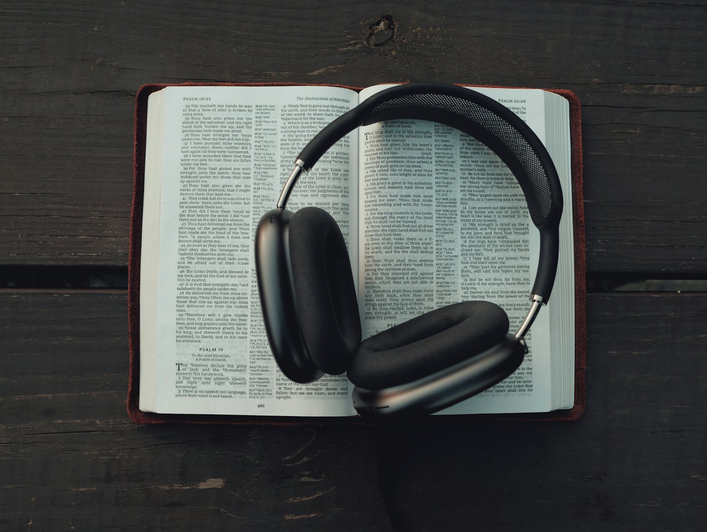 Cuffie nere appoggiate sulle pagine aperte di una Bibbia.